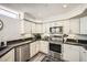 Well-lit kitchen featuring white cabinets, stainless steel appliances, and wood flooring at 7400 E Gainey Club Dr # 206, Scottsdale, AZ 85258