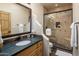 Bathroom with a decorative mirror, earth-tone tiles, and an enclosed shower with glass doors at 9802 E Hidden Valley Rd, Scottsdale, AZ 85262