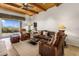 Cozy living room with wood-beamed ceilings, stone flooring, leather seating, and mountain views at 9802 E Hidden Valley Rd, Scottsdale, AZ 85262
