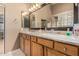 Bathroom featuring double sinks, granite countertops, wood cabinets, and glass block window at 10413 E Emelita Ave, Mesa, AZ 85208