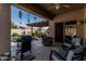 Inviting covered patio with grill, comfortable seating, and views of the backyard pool and pergola at 10413 E Emelita Ave, Mesa, AZ 85208