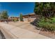 View of the house's front yard, showing the desert-style landscaping and the three-car garage at 10413 E Emelita Ave, Mesa, AZ 85208