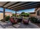 Backyard outdoor living space featuring a pergola, comfortable seating, and manicured landscaping at 10413 E Emelita Ave, Mesa, AZ 85208