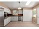 A spacious kitchen featuring white cabinets, stainless steel appliances, and a modern hanging light fixture at 10621 W Oakmont Dr, Sun City, AZ 85351