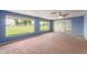 Bright living room with large windows, ceiling fan, and neutral carpet at 10621 W Oakmont Dr, Sun City, AZ 85351