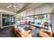 This bright sunroom features comfortable seating, a ceiling fan, and screened windows for outdoor enjoyment at 16842 N 103Rd Dr, Sun City, AZ 85351