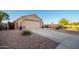 Tan stucco home features a well-manicured desert landscape and a two-car garage at 17416 W Ventura St, Surprise, AZ 85388
