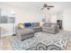 A living room with a gray sectional sofa, patterned rug, ceiling fan, and window at 17416 W Ventura St, Surprise, AZ 85388