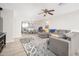 A living room with a gray sectional sofa, patterned rug, ceiling fan, and dining area beyond at 17416 W Ventura St, Surprise, AZ 85388