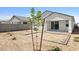 Rear house view with dirt yard, small trees, and gray concrete slab and border at 17830 W Mission Ln, Waddell, AZ 85355