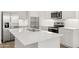 Modern kitchen featuring stainless steel appliances, white cabinets, and a large island with a sink at 17830 W Mission Ln, Waddell, AZ 85355