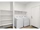 Clean laundry room with washer, dryer, shelving, and white door to outdoors at 17830 W Mission Ln, Waddell, AZ 85355