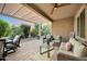 Relaxing covered patio with comfortable seating, dining area, and beautifully landscaped backyard at 20194 N Riverbank Rd, Maricopa, AZ 85138