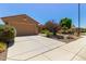 Single-story home with a two-car garage and desert landscaping featuring beautiful rocks and thriving plants at 21893 N 261St N Ave, Buckeye, AZ 85396