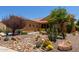Single-story home with a two-car garage and desert landscaping featuring beautiful rocks and thriving plants at 21893 N 261St N Ave, Buckeye, AZ 85396