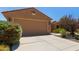 Single-story home with a two-car garage and desert landscaping featuring beautiful rocks and thriving plants at 21893 N 261St N Ave, Buckeye, AZ 85396