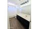 Bathroom with laminate floors, black cabinets, white sink and shower with curtain at 22523 W Pima St, Buckeye, AZ 85326