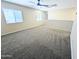This bonus room features neutral walls, carpet, a window, and a ceiling fan at 22523 W Pima St, Buckeye, AZ 85326