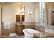 Bright bathroom featuring a soaking tub, double sinks with wood cabinets, tile accents, and plantation shutters at 5610 E Sanna St, Paradise Valley, AZ 85253