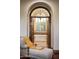 Relaxing bathroom retreat featuring a chaise lounge, arched doorway, and a luxurious soaking tub at 5610 E Sanna St, Paradise Valley, AZ 85253