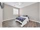 Neutral bedroom with wood-look floors, white trim, ceiling fan, and large window at 11952 W Villa Chula Ln, Sun City, AZ 85373