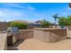 Outdoor kitchen and bbq area with a luxurious built in grill and sparkling pool and lush trees at 1321 E Monteleone St, San Tan Valley, AZ 85140