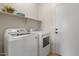 Convenient laundry room equipped with modern washer and dryer units, and storage shelves at 1321 E Monteleone St, San Tan Valley, AZ 85140