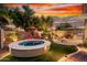 Backyard oasis featuring a cozy firepit, refreshing spa, and mature landscaping at 28878 N 127Th Ln, Peoria, AZ 85383