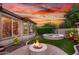 Backyard with spa, fire pit, and lush landscaping under a colorful sky at 28878 N 127Th Ln, Peoria, AZ 85383