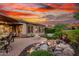 Outdoor space with brick patio, fire pit, waterfall, and lush landscaping, perfect for evening relaxation at 28878 N 127Th Ln, Peoria, AZ 85383