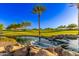 Picturesque golf course view featuring a serene pond and lush green fairways under a clear sky at 28878 N 127Th Ln, Peoria, AZ 85383
