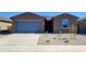 Inviting single-story home showcasing a two car garage, stone accents, and minimal desert landscaping at 37400 W San Sisto Ave, Maricopa, AZ 85138