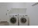 Laundry room features modern white washer and dryer with a convenient shelf and door access at 5902 E Juniper Ave, Scottsdale, AZ 85254