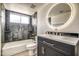 Modern bathroom boasts updated vanity, stylish round LED mirror, and tiled shower-tub combo at 7300 N Dreamy Draw Dr # 202, Phoenix, AZ 85020