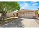 Inviting home featuring a two-car garage, well-manicured lawn, and a mature tree casting shade at 817 E Lamonte St, San Tan Valley, AZ 85140