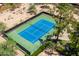 An aerial shot of a private, well-maintained blue and green tennis court surrounded by desert landscaping at 851 E Village Circle N Dr, Phoenix, AZ 85022
