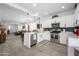 Open concept kitchen with stainless appliances, white cabinets and adjacent living area at 9238 W Roma Ave, Phoenix, AZ 85037