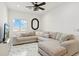 Comfortable living room features a large sectional sofa, ceiling fan, marble floors, and a large window at 9471 W Magnum Dr, Arizona City, AZ 85123