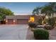 Well-maintained home exterior featuring a three-car garage, desert landscaping, and soft, welcoming lighting at 11299 E Greythorn Dr, Scottsdale, AZ 85262