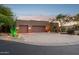 Desert home exterior with a wide driveway, two-car garage, desert landscaping and exterior lighting at 11299 E Greythorn Dr, Scottsdale, AZ 85262