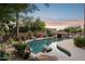 Beautiful backyard pool with a rock waterfall feature and vibrant desert landscaping at 11299 E Greythorn Dr, Scottsdale, AZ 85262