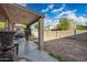 Covered patio and large backyard featuring mature landscaping and blue skies at 11383 W Pima St, Avondale, AZ 85323