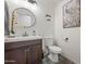 Cozy bathroom featuring a stylish vanity, round mirror, toilet and elegant peacock wall art at 11383 W Pima St, Avondale, AZ 85323