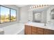 Bathroom with a large soaking tub, wood cabinets, and a vanity mirror showcasing the beautiful natural light at 2605 W Darrel Rd, Phoenix, AZ 85041