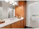 Bathroom with wood cabinets, double sinks, large mirror, and bedroom access at 2661 E Birchwood Pl, Chandler, AZ 85249