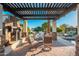 Inviting outdoor living space with a stone fireplace, pergola, and comfortable seating area by the pool at 2661 E Birchwood Pl, Chandler, AZ 85249