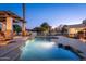Backyard pool with a waterfall feature and plenty of room for seating on the surrounding patio at twilight at 2661 E Birchwood Pl, Chandler, AZ 85249