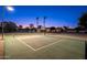 Illuminated tennis court with a basketball hoop in a large backyard, perfect for evening games at 2661 E Birchwood Pl, Chandler, AZ 85249