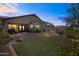 Backyard at dusk with synthetic lawn, landscaped areas, and covered patio creating a tranquil outdoor oasis at 3022 E Santa Fe Ln, Gilbert, AZ 85297