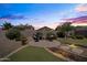 Backyard at dusk has a circular patio, artificial grass, and garden lighting creates a tranquil outdoor retreat at 3022 E Santa Fe Ln, Gilbert, AZ 85297